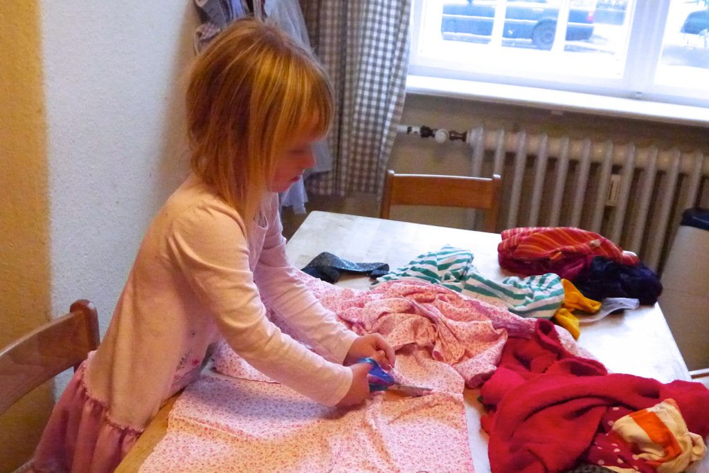 die Kinder zerschneiden Stoff für die Kleider der Puppen